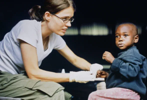 Volunteer helping a child, symbolizing StoneX's partnership with Save the Children.
