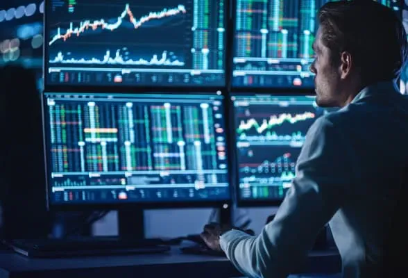 Trader analyzing multiple financial data screens, representing institutional-grade liquidity and FX trading solutions from StoneX Pro.
