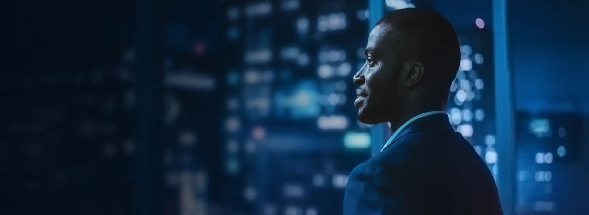 Business professional looking out over a city at night, symbolizing global clients relying on StoneX Pro's liquidity and expertise.