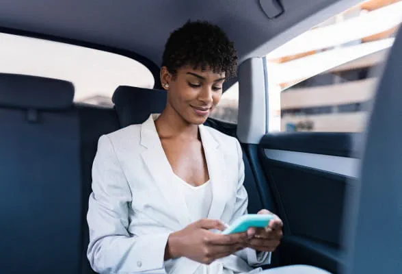 Professional using a smartphone in a car, highlighting StoneX Wealth Management's advanced platforms and technology for efficient account management