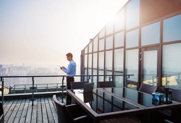 Professional using a smartphone on a rooftop, highlighting StoneX Wealth Management's support and resources for financial advisors