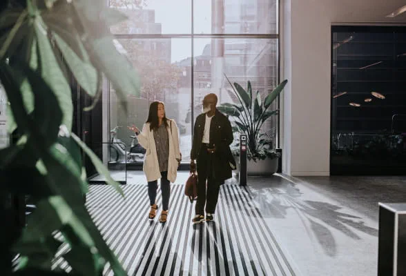 Two professionals walking in an office building, highlighting StoneX Wealth Management's Practice Solutions Group for growing and managing practices