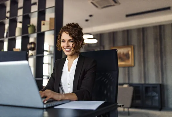 Woman working on a laptop, accessing StoneX's comprehensive glossary of financial terms and definitions