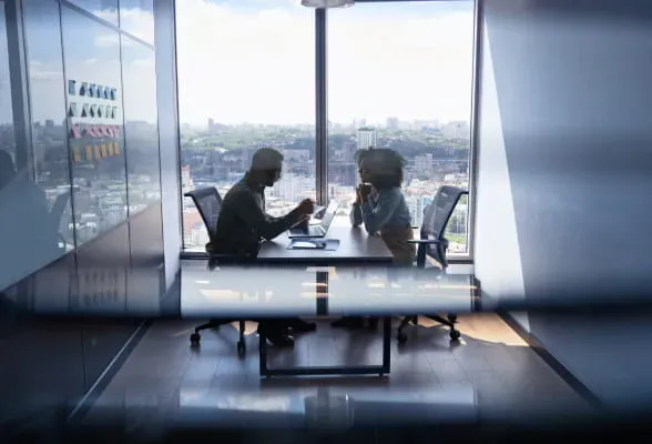 Two professionals in a meeting room, highlighting the option for financial professionals to join StoneX Wealth Management as employees