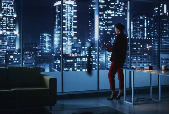 Professional standing by office windows at night, illustrating StoneX Wealth Management's support for RIA and IAR advisors with integrated platforms
