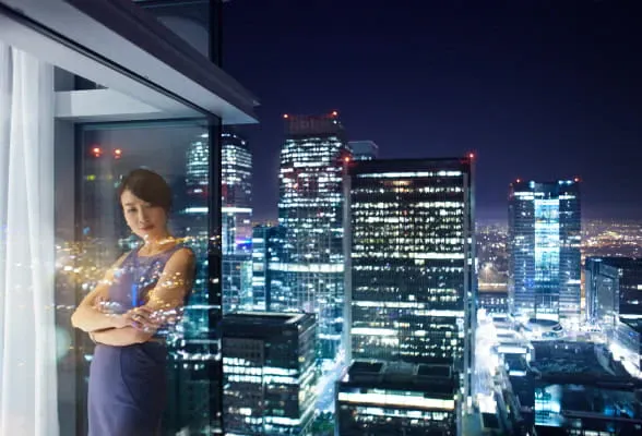 Professional standing by a window overlooking a city skyline, illustrating StoneX Wealth Management's tailored affiliation options
